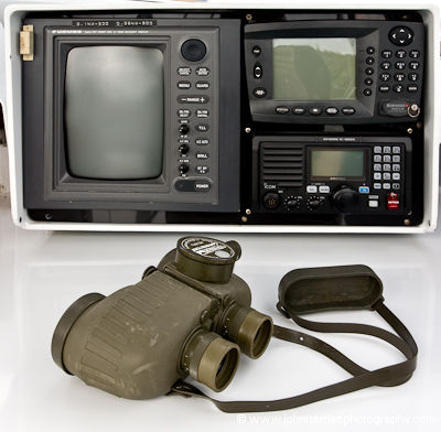 Sailboat electronics—a radar, GPS and VHF radio—in an aluminum pod at the cockpit chart table with a pair of Steiner binoculars in the foreground