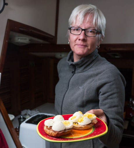 Phyllis holding a plate with eggs and bacon on a bagel