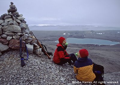 Two crew from aluminum sailboat Morgan's Cloud having fun at the cairn overlooking Kinnvika on Nordaustlandet, Svalbard