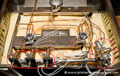 The Force10 stovetop showing the disassembled defective valve on the right and the three defective spark igniter control switches on the left, on aluminum expedition sailboat Morgan's Cloud