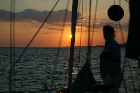 Woman on bow of sailboat at sunset